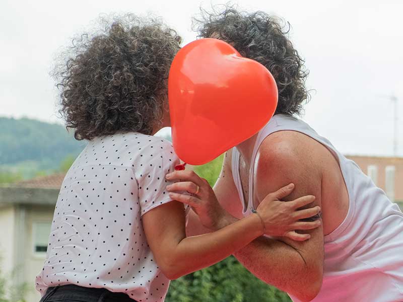 Bico de dous persoas tapado por un corazón de globo. Espectáculo de igualdade.